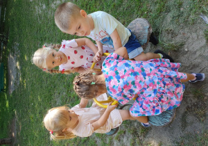 Dzieci bawią się w przedszkolnym ogrodzie na bujaku.