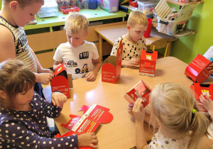 Dzieci składają kartonowe pudełka do segregacji zużytych baterii.