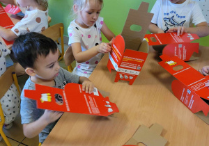 Dzieci składają kartonowe pudełka do segregacji zużytych baterii.