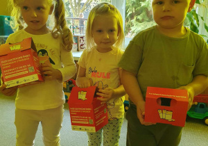 Dzieci trzymają pojemniki na zużyte baterie.
