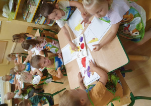 Dzieci malują farbami za pomocą dłoni i palców.