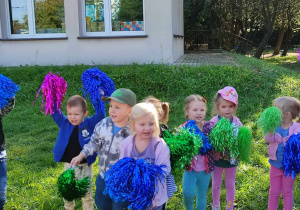Dzieci tańczą z kolorowymi pomponami.