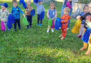 Dzieci tańczą z kolorowymi pomponami.