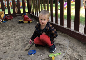 Chłopiec bawi się w piaskownicy.