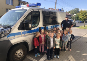 Dzieci z policjantem przed radiowozem