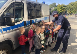 Dzieci z policjantem przed radiowozem