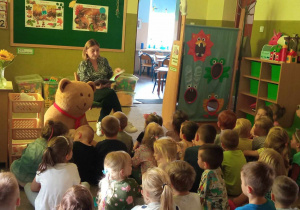 Dzieci słuchają opowiadania czytanego przez panią dyrektor.