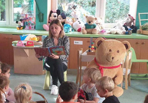 Dzieci słuchają opowiadania czytanego przez panią dyrektor.
