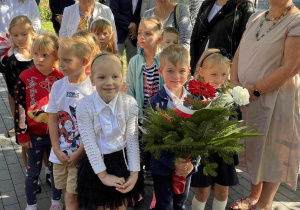 Dzieci składają kwiaty pod pomnikiem.