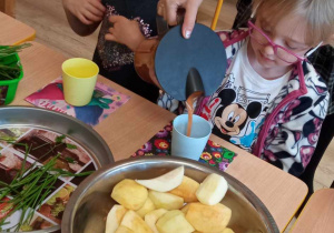 Dzieci przygotowują sok w sokowirówce.