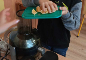 Chłopiec wrzuca składniki do sokowirówki.