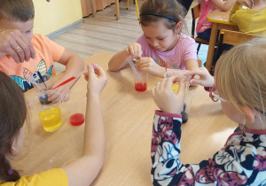 Dzieci przeprowadzają eksperyment z sody, oleju i octu z barwnikiem.