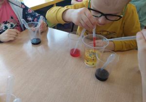 Chłopiec przeprowadza eksperyment z sody, oleju i octu z barwnikiem.