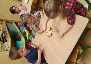 Dzieci nadziewają kawałki owoców na wykałaczki.