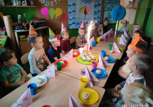 Dzieci przy urodzinowym stole przyglądające się płonącej fontannie.