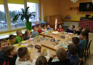Dzieci siedzą przy stole z słodkimi przekąskami