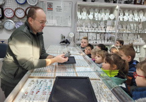 Dzieci obserwują narzędzia, którymi pracuje zegarmistrz.