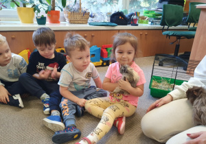 Dzieci przytulają świnkę morską.