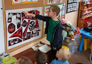Chłopiec pokazuje na planszy przedmioty, w których nazwach zawarta jest poszukiwana litera