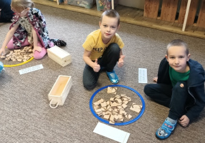 przedszkolaki układaja literę z drewnianych klocków