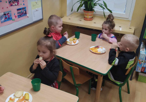 Dzieci jedzą przyniesione przez rodziców przekąski.