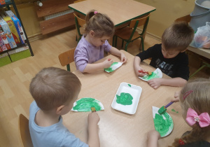 dzieci malują farbą papierowe talerzyki.
