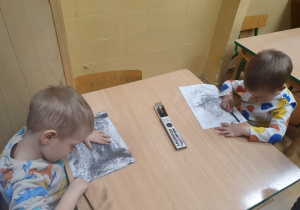 Dzieci malują węglem drzewnym.