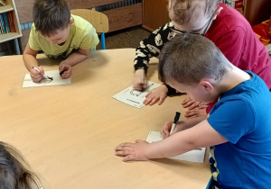 dzieci piszą litery po śladzie