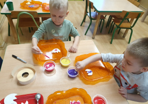 Dzieci barwią płatki kosmetyczne za pomocą pipety.