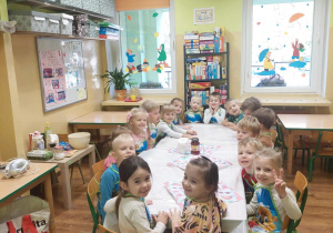 Dzieci siedzą przy stole w oczekiwaniu na gofry.