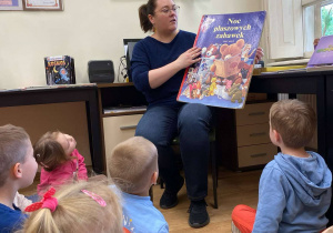 Pani bibliotekarka pokazuje dzieciom największą książkę.