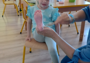 dziewczynka ma pomalowaną stopę na kolor różowy