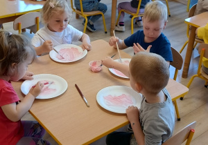 przedszkolaki malują papierowe talerzyki na różowo