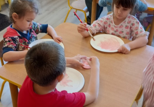 przedszkolaki malują papierowe talerzyki na różowo