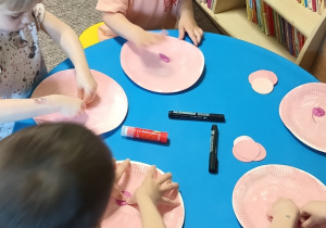 dzieci przyklejają różówą plastelinę