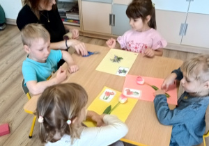 dzieci przyklejają kwiaty na kartę