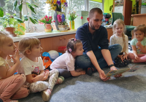Tata dziewczynki czyta przedszkolakom.
