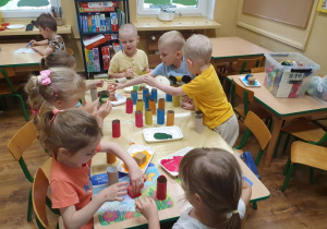 Dzieci malują rolki od papieru na wybrane kolory.