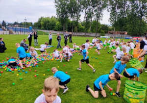 Dzieci zbierają piłki do wyznaczonego kosza.