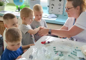 Dzieci oglądają przybory medyczne, z których korzysta pielęgniarka.