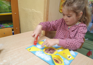 Dziewczynka wykonuje pracę plastyczną.