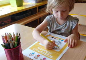 Dziewczynka koloruje pojemniki na śmieci.