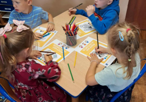 Dzieci rozwiązują zadania w kartach pracy.