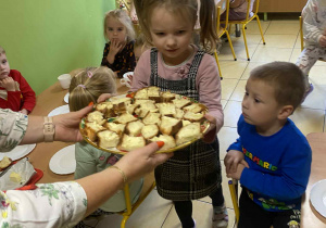 Dziewczynka częstuje chałką.