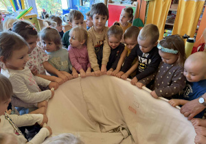Dzieci szukają w worku pluszowej stonogi.