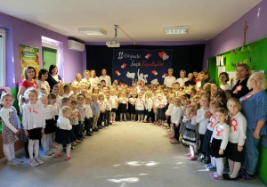 Dzieci i pracownicy przedszkola śpiewają hymn.