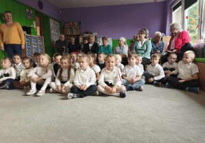 Goście i przedszkolaki oglądają występ starszaków.