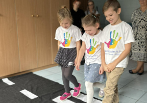 Dzieci przechodzą przez rozłożoną matę obrazującą przejście dla pieszych.