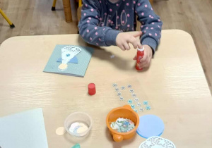 dziewczynka ozdabia kartę świąteczną