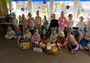 Dzieci z zebranymi w przedszkolu herbatkami dla seniorów.